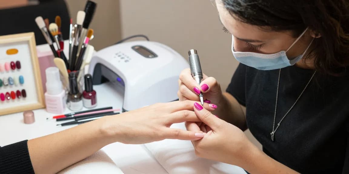 Tehnician de unghii iscusit aplicând gel constructie unghii într-un salon elegant.